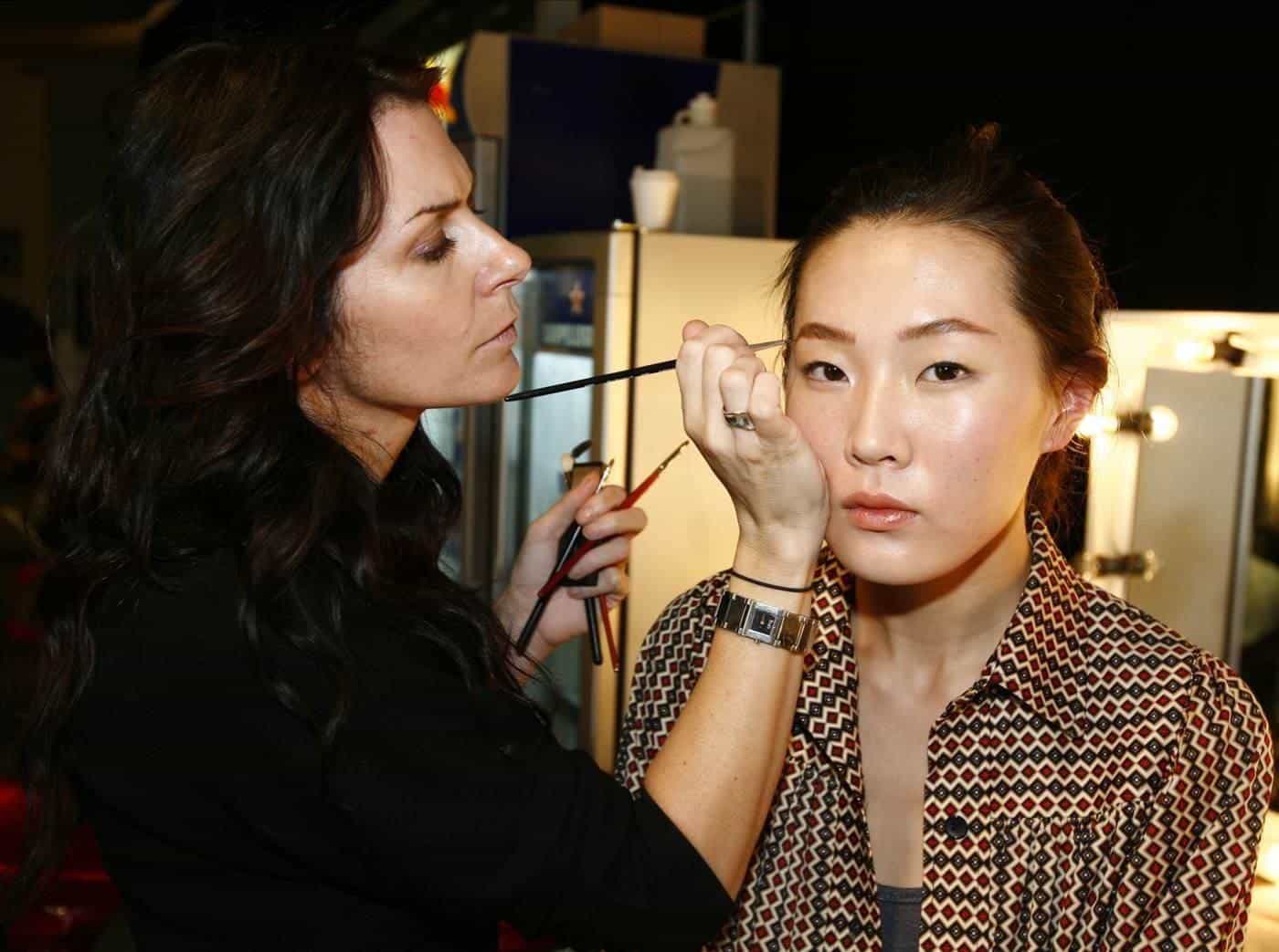 A make-up artist preparing a model backstage