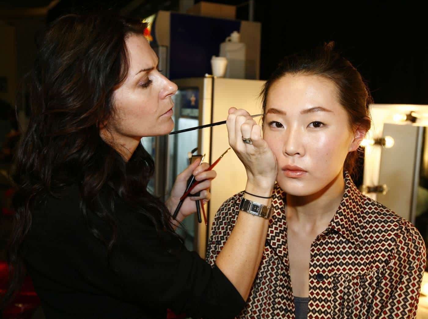 A make-up artist preparing a model backstage