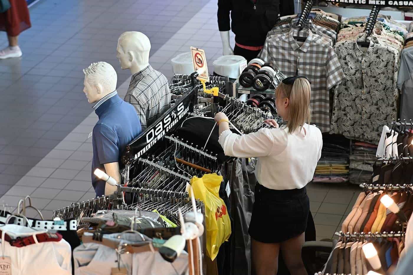 Shirts and tops on a crowded clothing rack in a store
