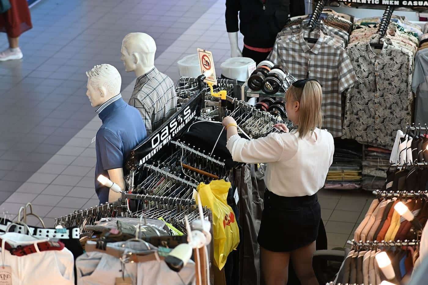 Shirts and tops on a crowded clothing rack in a store