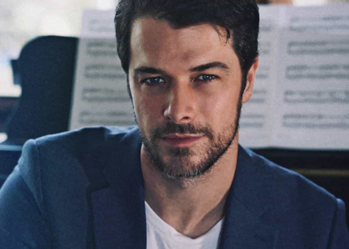A professional headshot of a man in a blue blazer